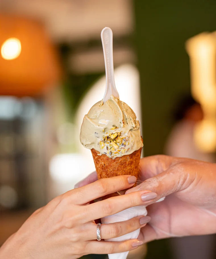 Casquinha de gelato de pistache segurada na mão, em jardim