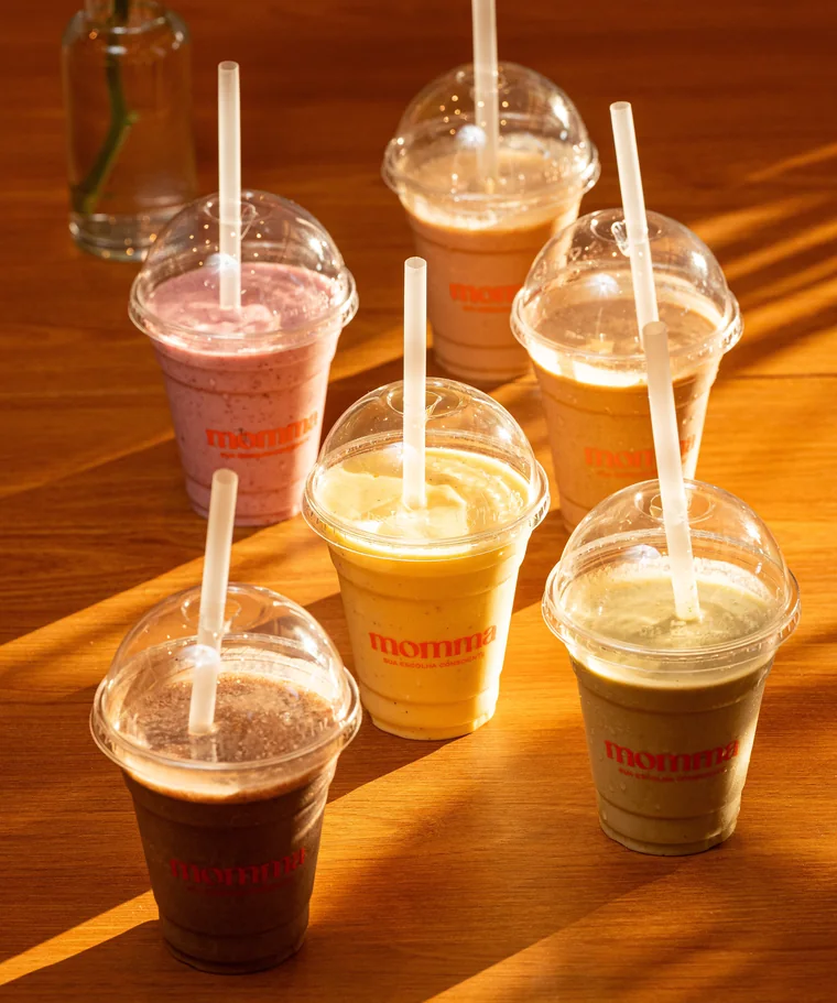 Copos de smoothies proteicos da Momma sobre mesa de madeira